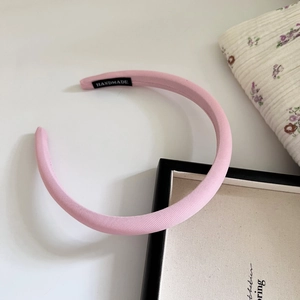 Detail eines rosa Stoff-Haarreifens mit einem schwarzen Handmade-Etikett auf der Innenseite
