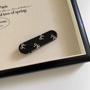 Vista dettagliata di una clip per capelli ovale nera lucida con mini fiocchi in argento