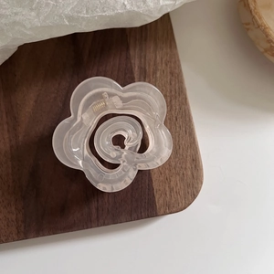 Vue détaillée d'une pince à cheveux camélia crème mate sur un support en bois de noyer