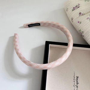 Detail von rosa kariertem Schwamm-Stirnband mit handgefertigtem Etikett aus Stoff