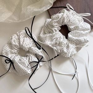 Detailed view of white polka dot scrunchies with long elegant ribbon bow accents