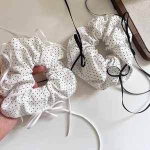 Detail shot of black and white polka dot scrunchies with long ribbons on white surface