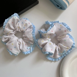 Detail of sweet heart-print hair scrunchies with light blue plaid ruffled edges and a bow