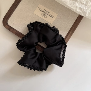 Premium black satin scrunchie with beaded edges on a rustic wooden display tray