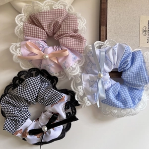 Three sweet plaid scrunchies with lace edges, pearls and bows on a cream background