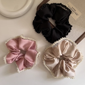 Detailed view of satin scrunchies with elegant pearl edges in black, pink, and champagne gold