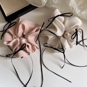 Rosafarbene und beige Satin-Haargummis mit schwarzen Bändern in der Draufsicht