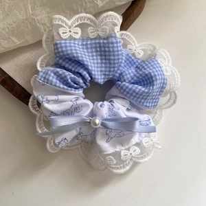 Detailed view of plaid scrunchie with white lace edges, blue ribbon and pearl accent