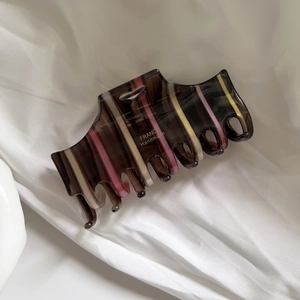 Close-up of striped acetate hair claw clip with France Handmade gold lettering detail