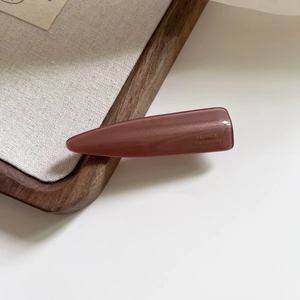 Detailed close-up of a pink acetate hair clip featuring gold France Handmade lettering