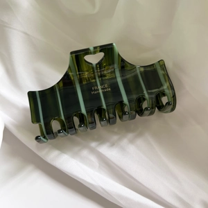 Close-up of dark green striped acetate hair claw with heart cutout and gold lettering