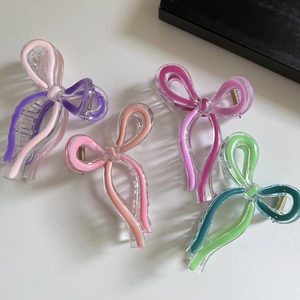 Detailed macro view showing four colorful acrylic butterfly hair claws with metal springs