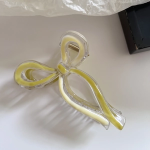 Detail of transparent bow claw clip with fresh lemon yellow inlay and golden spring