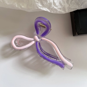 Detail of purple and pink acrylic bow hair claw clip showing metallic spring mechanism