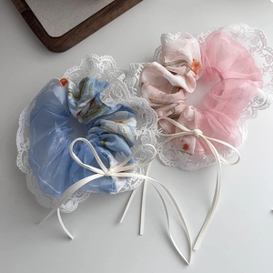 Detailed close-up of light blue and pink floral organza hair scrunchies with lace trim