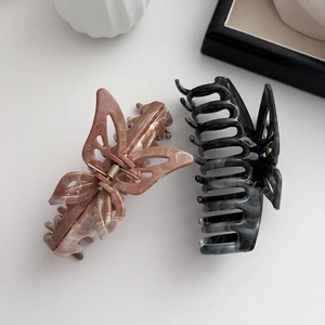 Detailed top view of large ink-wash butterfly hair claws in pink and grey marble finish