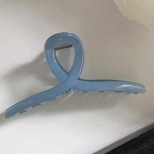 Detail of a 13cm light blue translucent jelly hair claw clip with silver metal spring