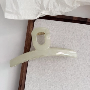 Détail d'une pince à cheveux vert gelée de 13cm sur un fond en lin élégant