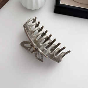 Close-up of marble pattern hair claw clip featuring an intricate butterfly cutout design