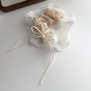 Close-up of floral chiffon scrunchie with lace trim and elegant ribbon bow detail