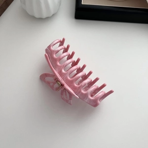 Detail of pink marble textured resin hair claw clip with butterfly wing hollow design