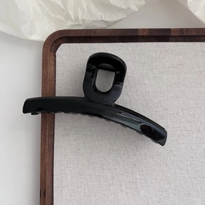 Vue détaillée d'une pince à cheveux noire brillante de 13cm sur un support en tissu