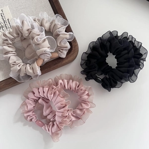 Detailed view of three elastic mesh hair scrunchies in beige black and lotus pink colors