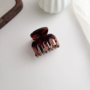 Macro detail of tortoiseshell hair claw clip with glossy finish on a minimalist background