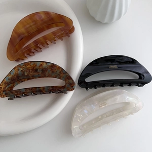 Close-up of four French acetate hair claws with marble patterns and gold handmade logo