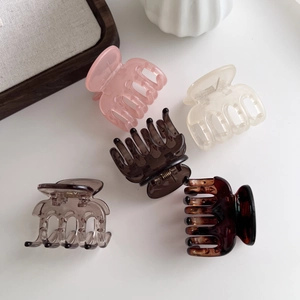 Detailed top view of five elegant hair claws in assorted neutral shades on white surface