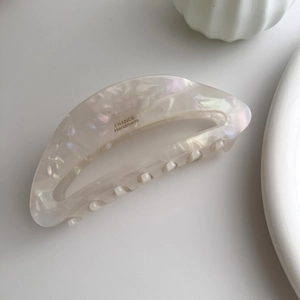 Detail view of handmade cream acetate hair claw clip with marbled texture and gold engraving