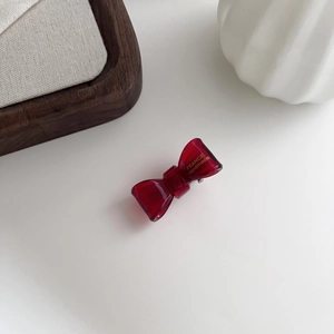 Detail view of handmade translucent burgundy acetate bow hair clip with gold lettering