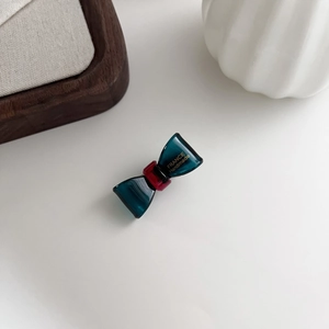 Detail of dark cyan bow hair clip with gold France Handmade logo and red center