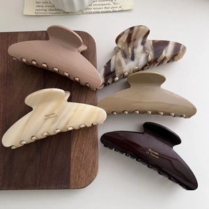 Five-piece set of large acetate hair claws in neutral tones with gold brand engraving