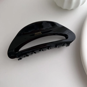 Detail of glossy black acetate hair claw clip with golden France Handmade lettering
