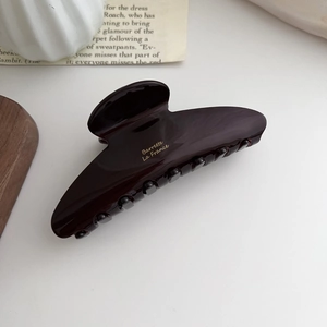 Close-up of deep brown glossy hair claw with gold Barrette La France text engraving
