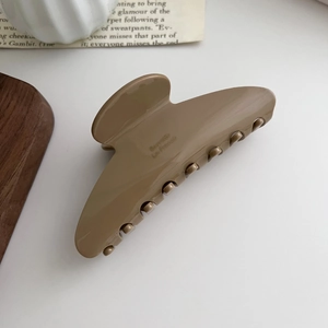 Detailed close-up of a large milk tea colored hair claw clip with glossy resin finish