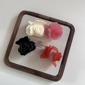 Pinces à cheveux en forme de rose 3D en quatre couleurs sur un plateau en bois