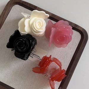 Détail de quatre pinces à cheveux rose en acétate en crème, rose, noir et corail
