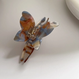 Dettaglio della grande pinza per capelli a farfalla in acetato con motivi marmorizzati blu