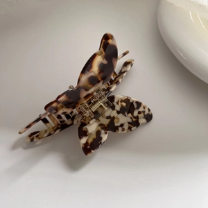Dettaglio del mollettone a farfalla tartarugato con molla in metallo dorato