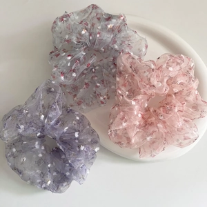 Drei florale Organza-Haargummis in Pastellfarben auf einem weißen Tablett