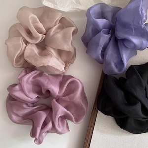 Detail of four large pearlescent organza scrunchies in gold, violet, grey-pink, and black