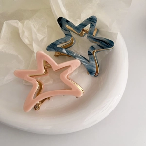 Star-shaped acetate claw clips in pink and marble blue with gold metal hardware