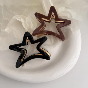 Detail of star-shaped acetate hair claws in black and brown with gold metal springs