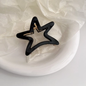Detailed close-up of a star-shaped black hair claw clip with golden metal spring