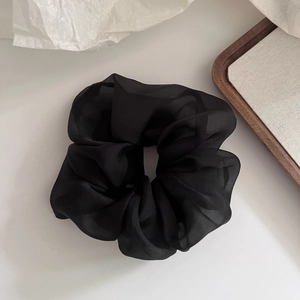 Detailed view of the sheer black tulle scrunchie with soft pleats and elegant volume