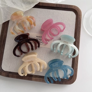 Macro shot of assorted acetate pumpkin-shaped hair claws in multiple colors on a wooden tray