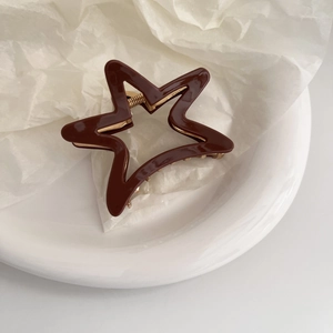Detail of hollow star hair claw with glossy chocolate finish and gold metal spring