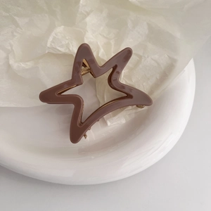 Detail of a brown star-shaped acetate hair claw clip with a strong metal spring